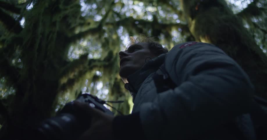 Man takes photos with professional camera surrounded by hanging forest moss