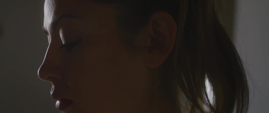 Close up of a young womans face inside a dimly lit room