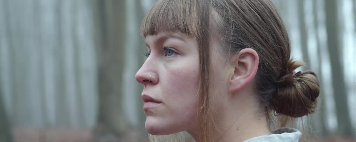 A woman is standing in a forest during the day