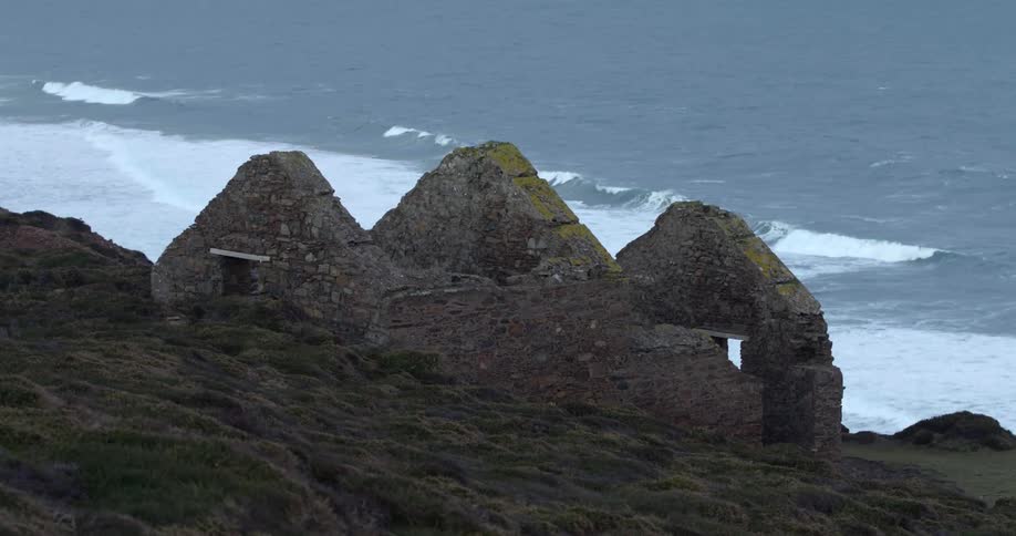 Ruins of an abandoned cobblestone house on a cliff near the ocean