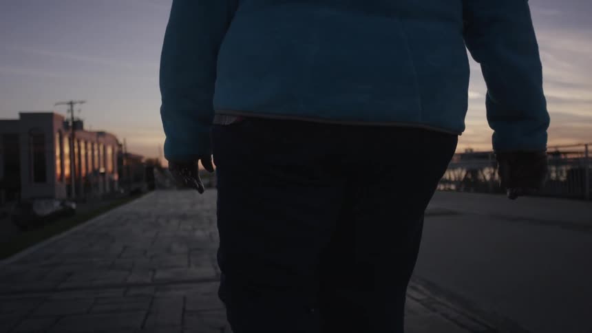 A man is walking along a pier at sunset