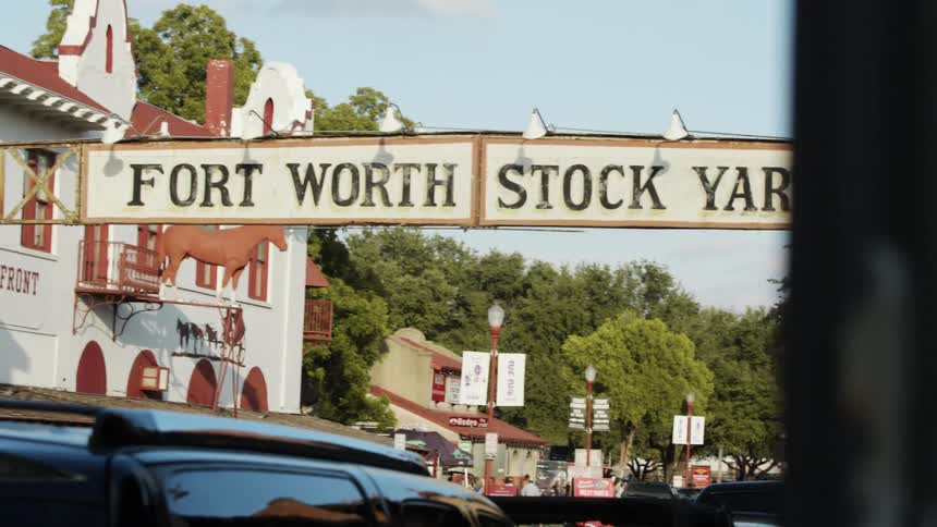 People walk around the business district of a city near the entrance with a large arched sign