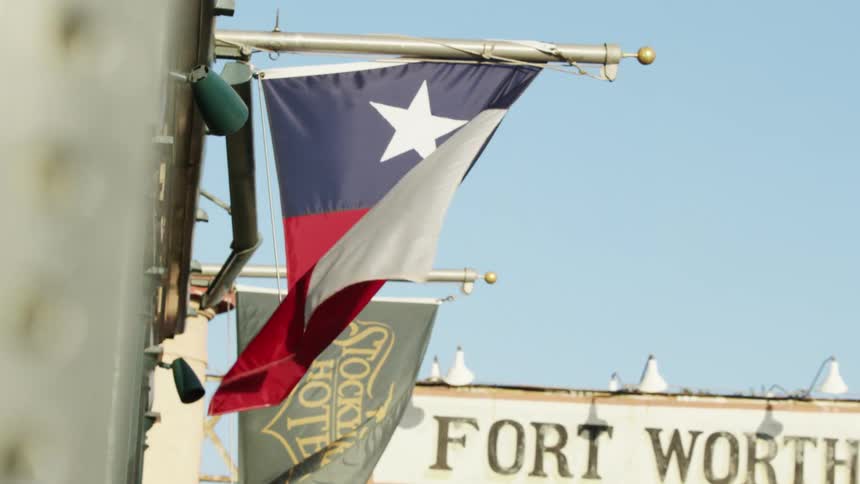 A flag is blowing in the wind and attached to a store