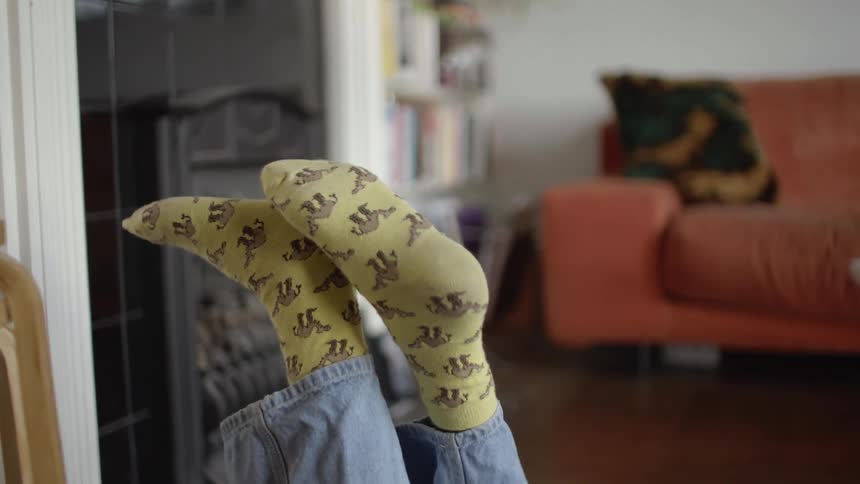 Close up of the yellow printed socks of a girl laying over a rug in the living room