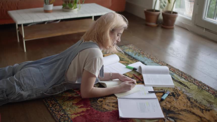 Teenager girl studying on the carpet of her living room