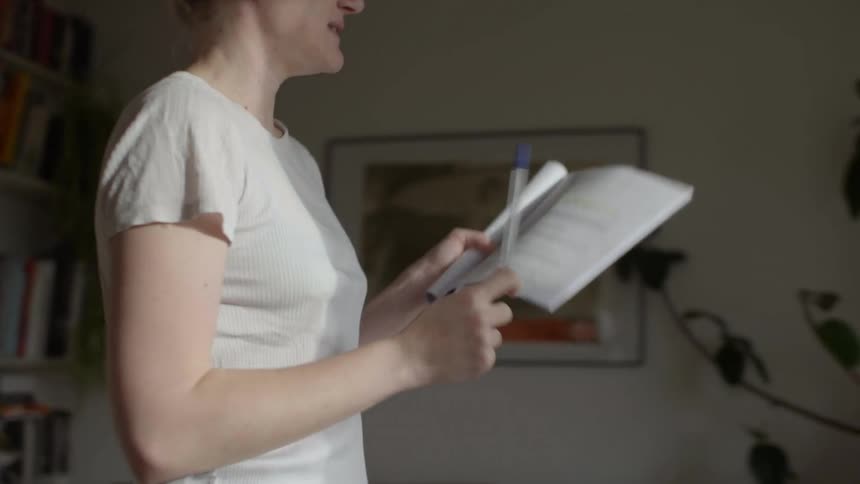 A woman is practicing a speech from a booklet in her hands