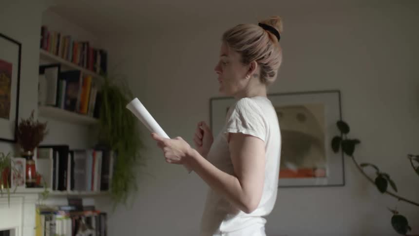 A woman paces in an office while reading out loud from a booklet