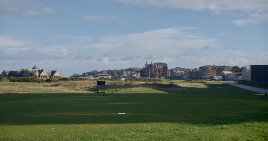 Green grass on a golf course next to a city at day time