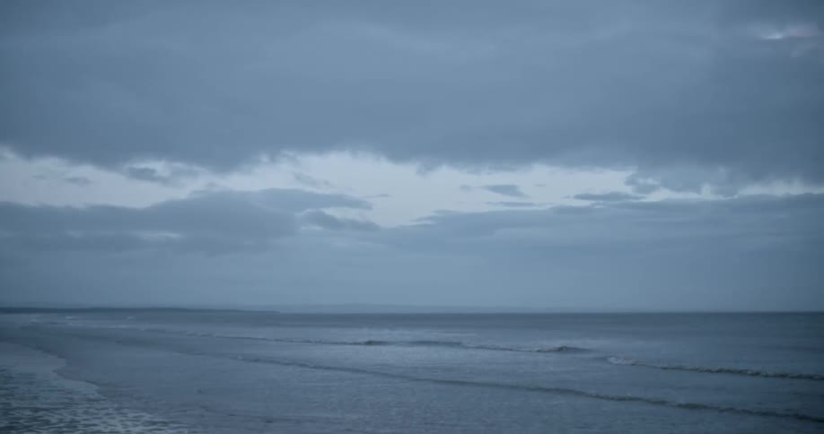 Waves roll in on coast on cloudy day