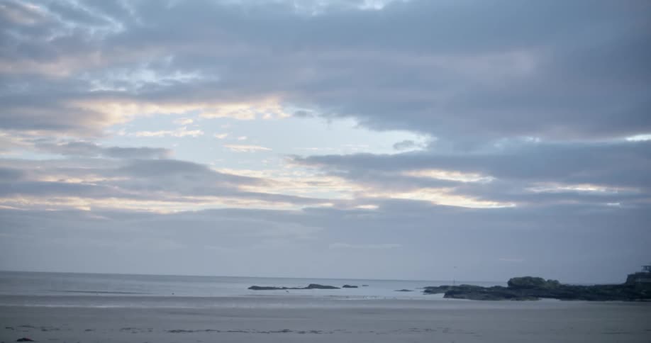 A beach with sand with the ocean sky and clouds in the background