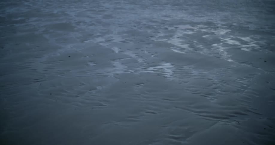 A landscape with sand and puddles of water