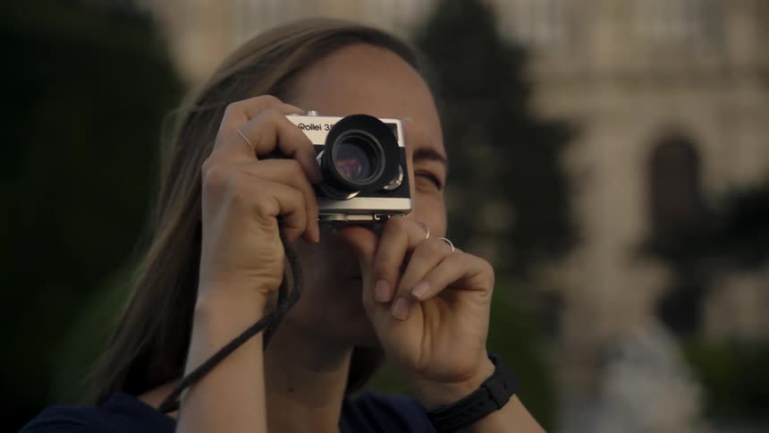 A woman is taking pictures with a camera outdoors