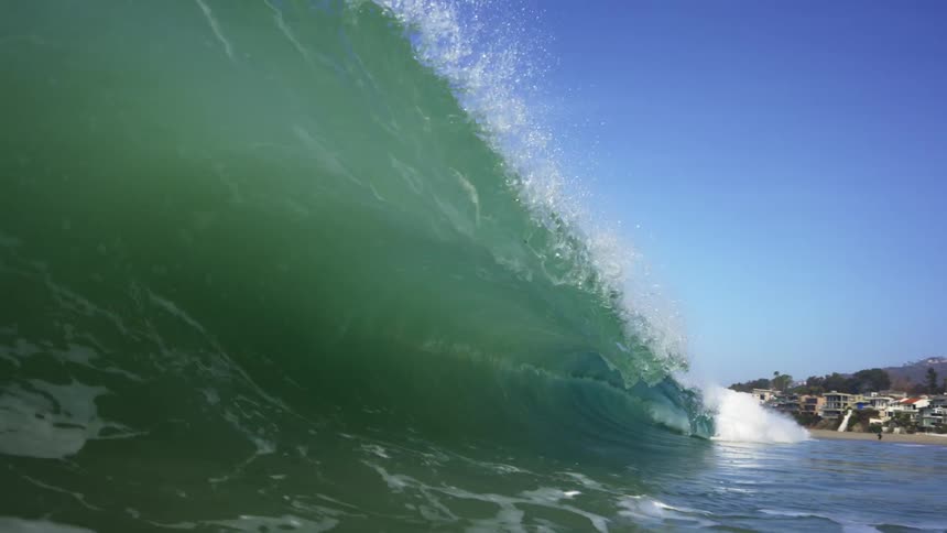 Big wave rolls in splashing over head on a clear day