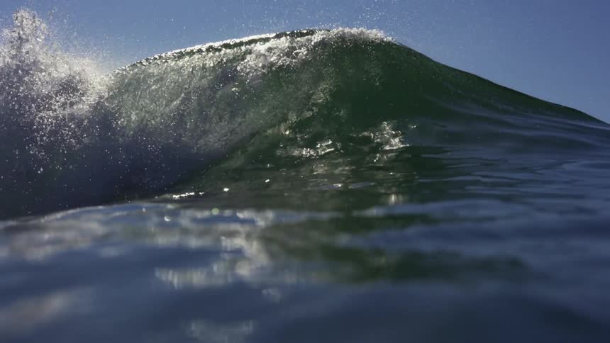 An ocean wave crashing down in a sea on a sunny day
