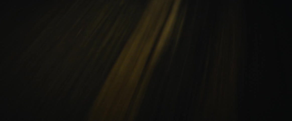 A car with bright headlights being driven on a road at night