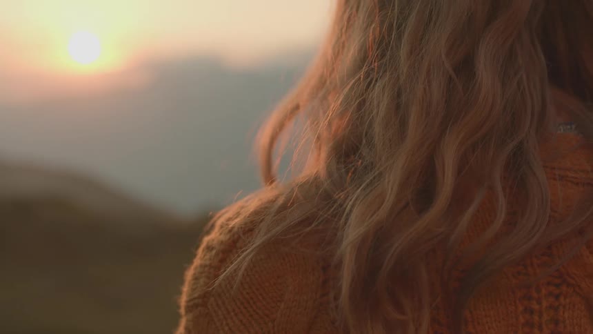 A woman is standing outdoors at dusk