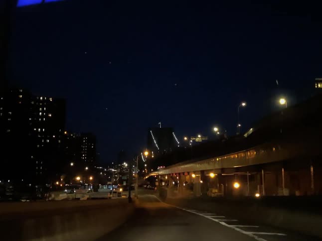 Cars are driving in a city at night