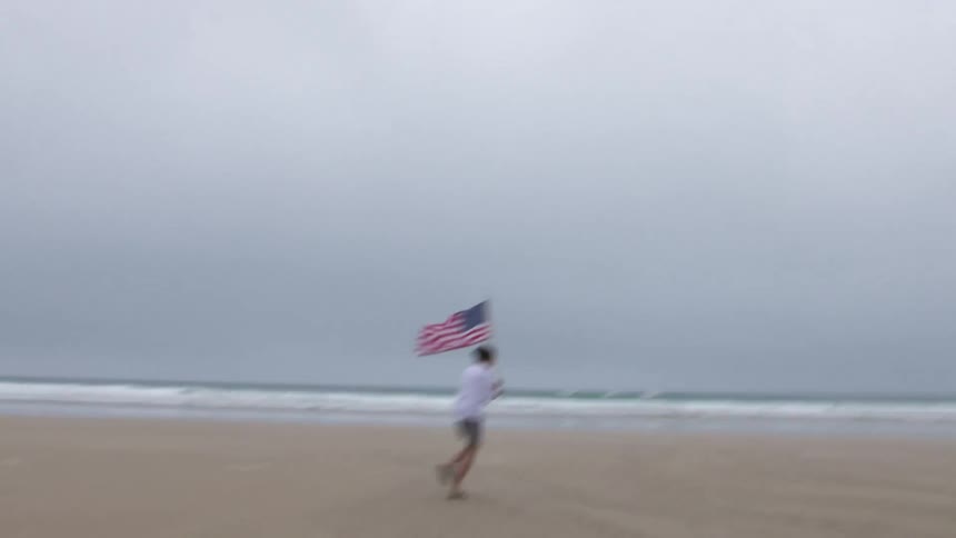 A man running on a beach with a flag