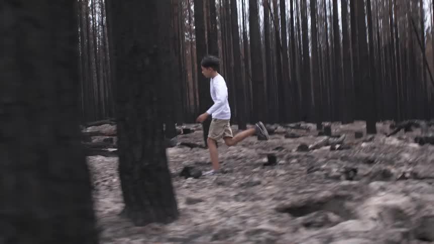 A teenage boy running through a forest