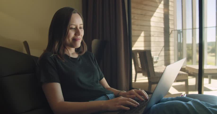 A woman is typing on a laptop while sitting indoors