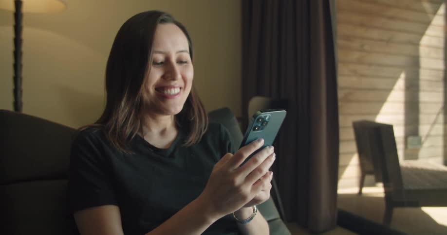 A woman sitting with a phone smiling