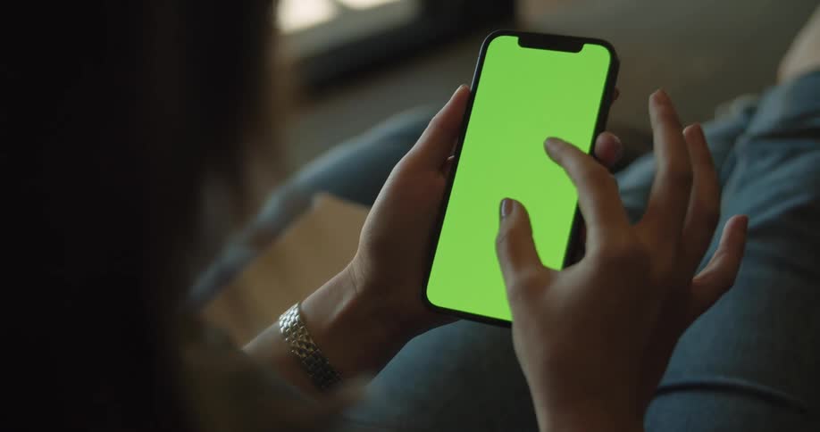 A woman is using her phone while sitting on a chair indoors