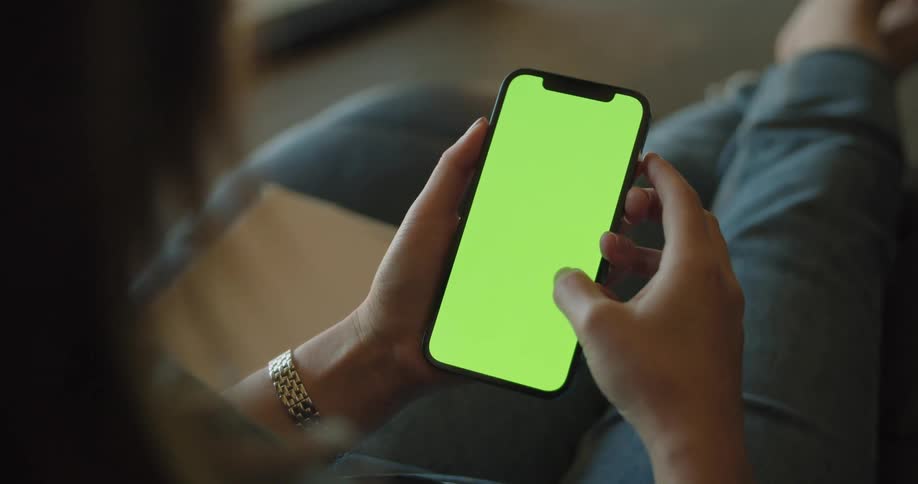 A woman is sitting on a chair indoors and looking at her cellphone
