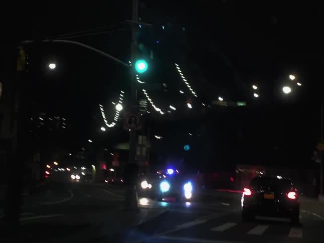 Driving in a car down a street with traffic and emergency lights flashing near a bridge