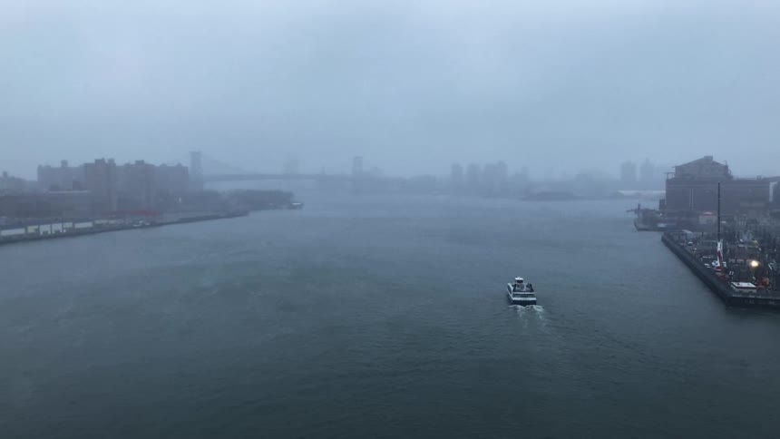 Boats on a body of water with a skyline and foggy weather