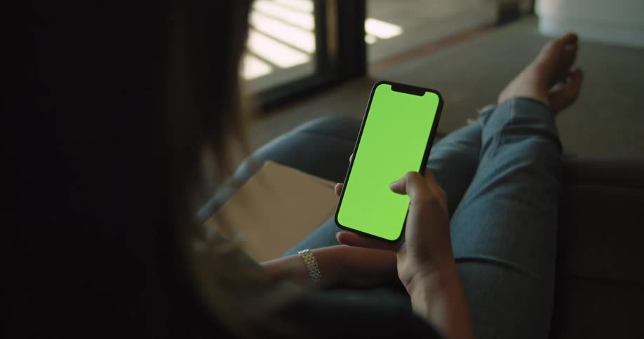 A woman sits with her feet up scrolling on her phone