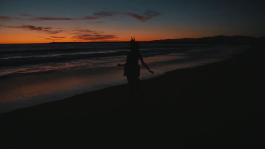 A woman running on the beach as the sun sets