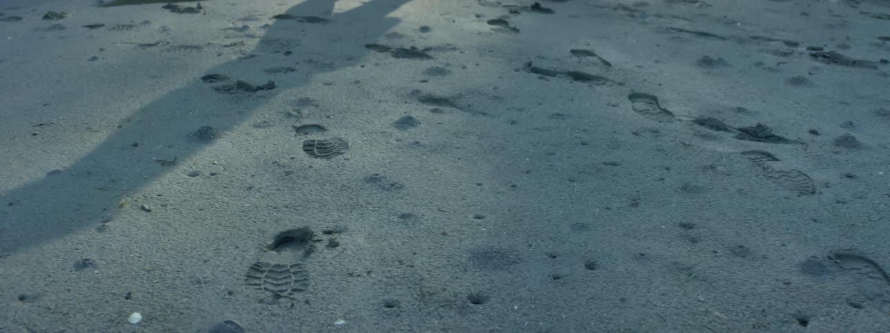 A persons shadow shows against snow covered ground covered in footprints