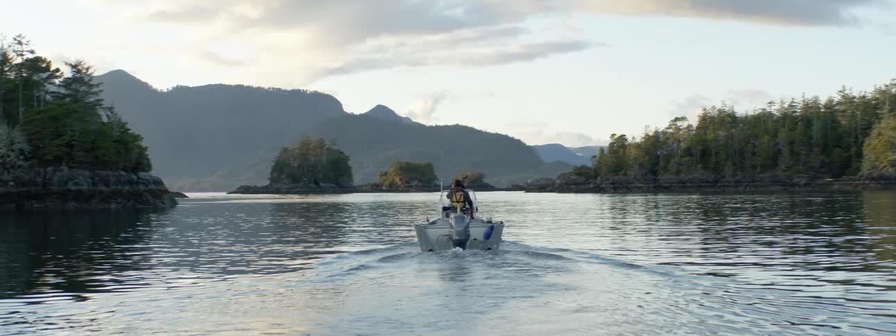 Boat traveling over the calm river waters near the mountains at sunset