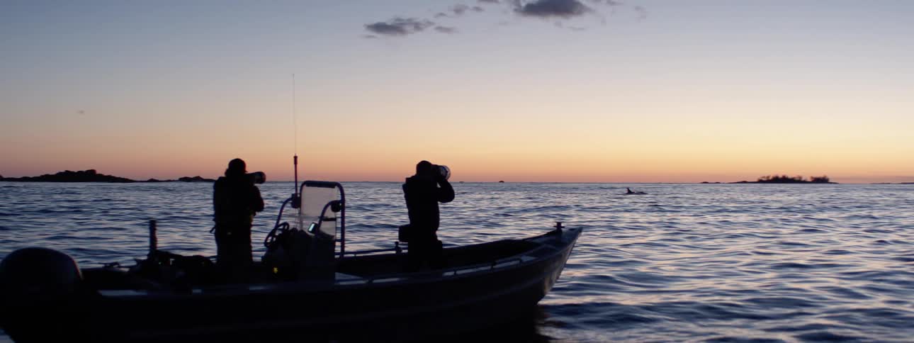 Two people are on a boat on the lake at dusk