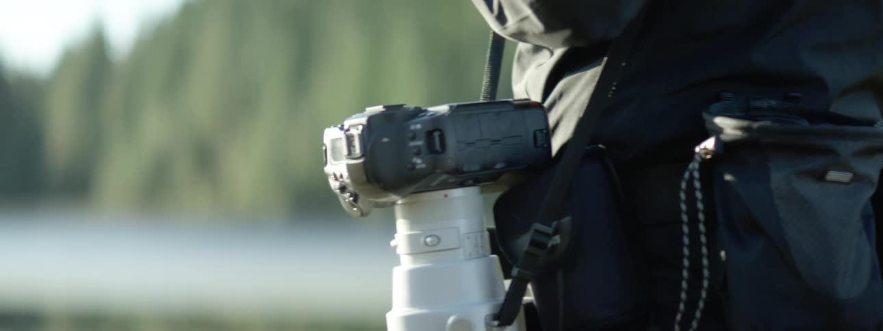 A person is holding a camera with a large lens