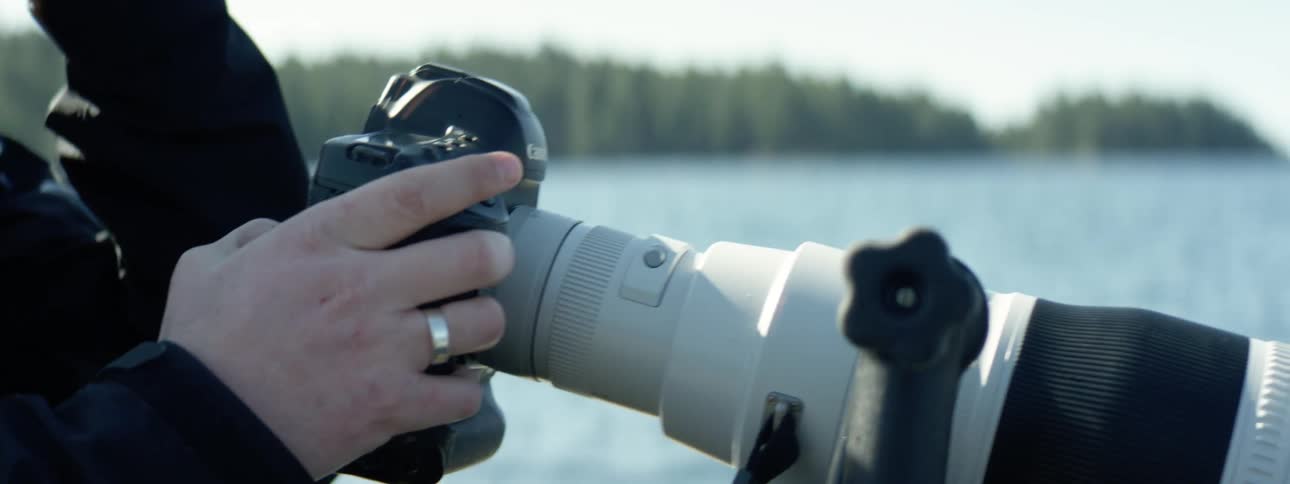 A photographer in a boat on a lake is scrolling through photos on a camera