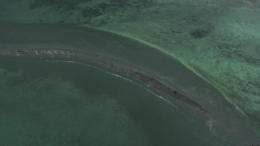 A person walking on a shore with water