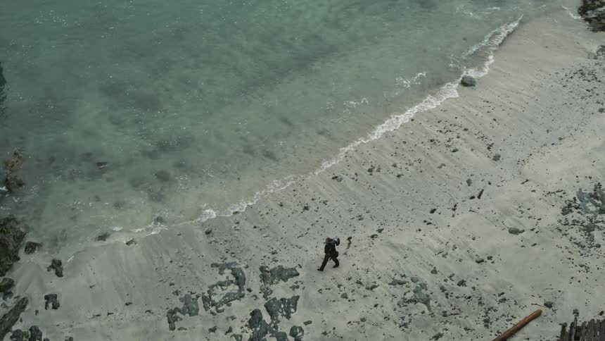 A person with a camera walking on a shore