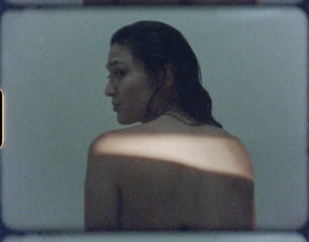 Young woman with wet hair turns around to look at the camera whilein the shower