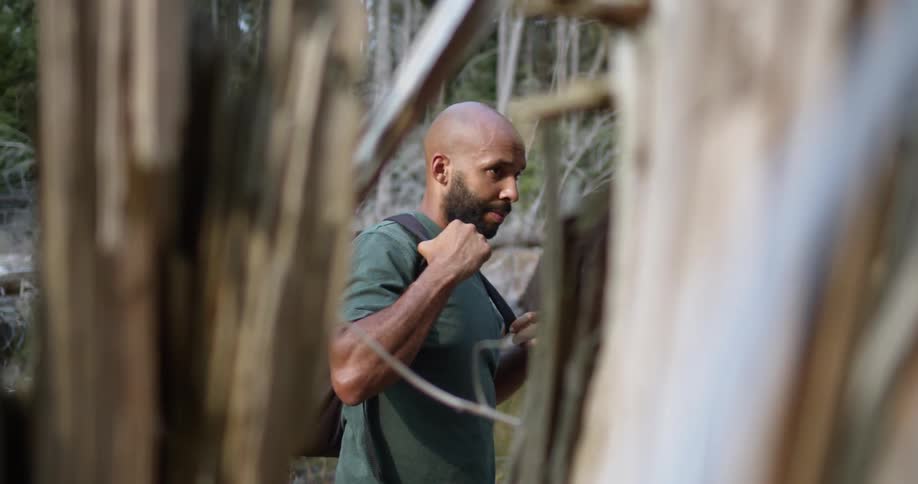 A man hiking in the forest adjusts his backpack