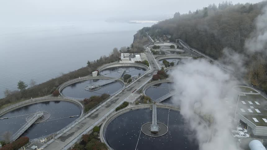 Seagulls float on and fly above filtration tanks at a large wastewater treatment facility