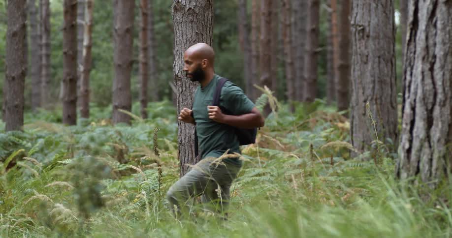 A hiker holds the straps of his backpack as he walks through the brush
