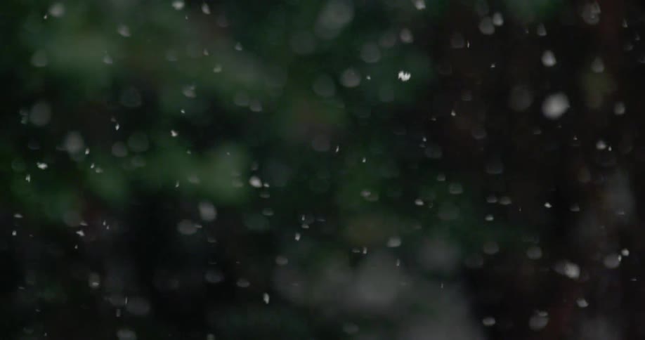 Snow falling on to a park bench and grass