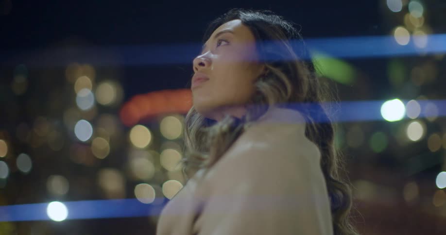 A woman standing outside looking up at the city lights