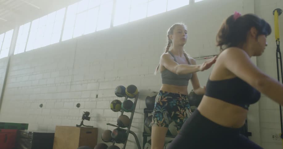 Fit young blonde woman wearing sports clothes coaching a student in a gym