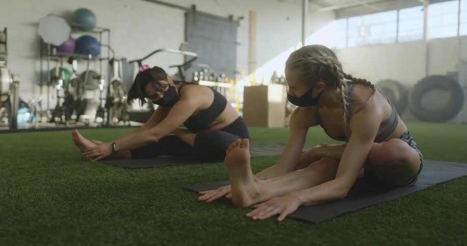 Two women stretch as they exercise