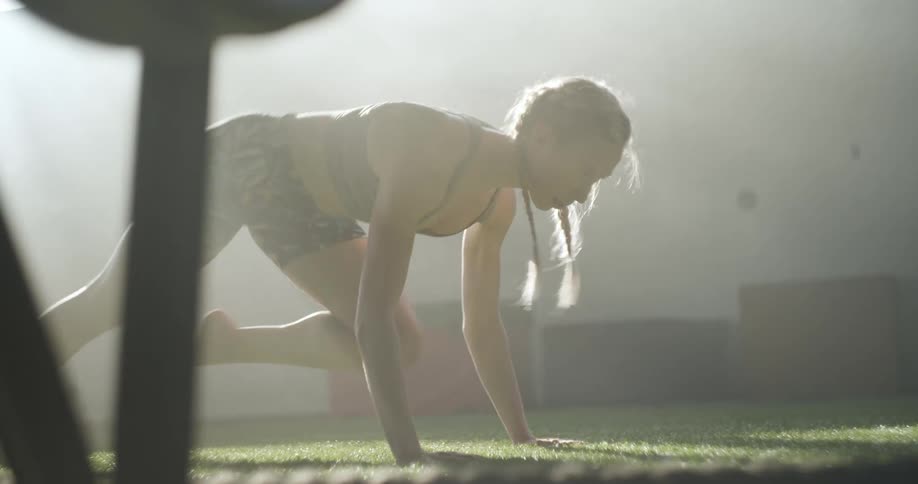 A woman with pigtail braids does running planks outdoors