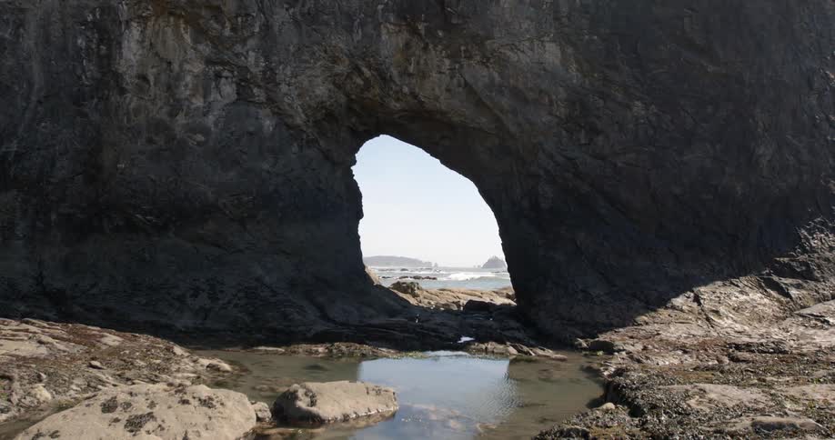 A small doorway is in the middle of this huge rock by the shore