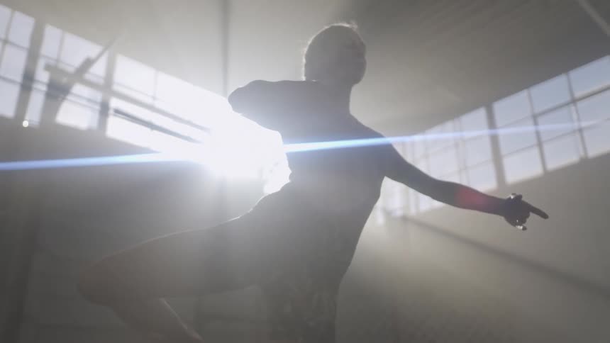 A young woman performs yoga poses in a dimly lit building during the day