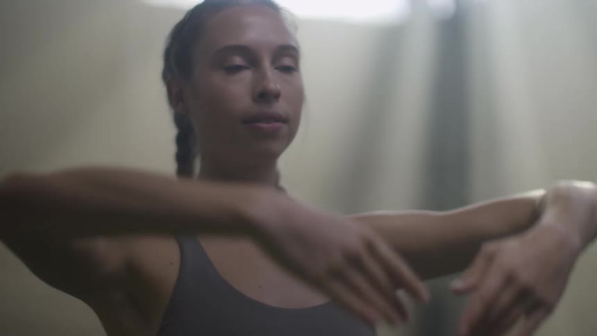 A woman is stretching indoors during the day